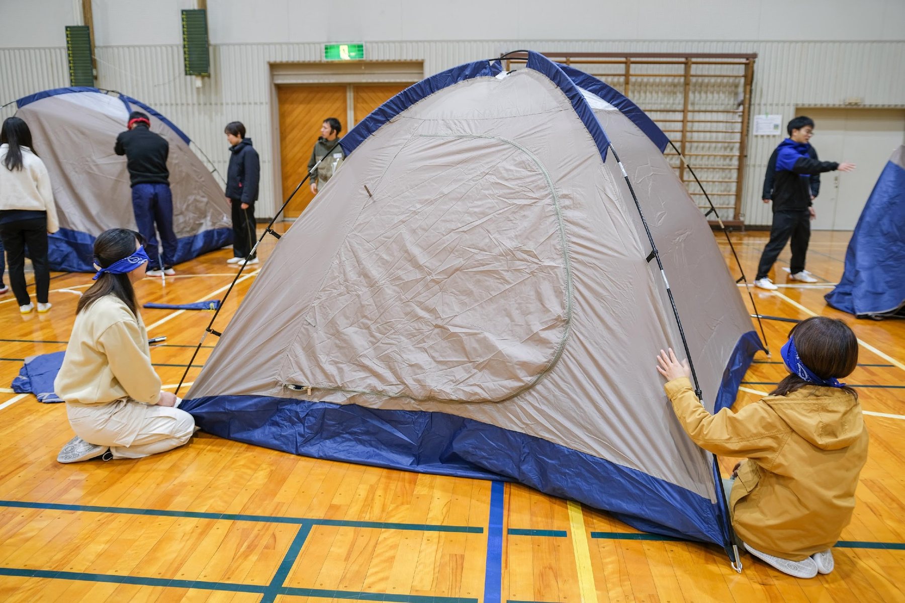 体育館でテント設営に取り組む研修参加者